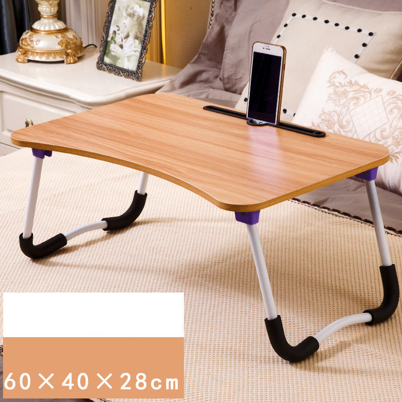 Foldable wooden desk with adjustable legs on a carpeted floor, next to a sofa.