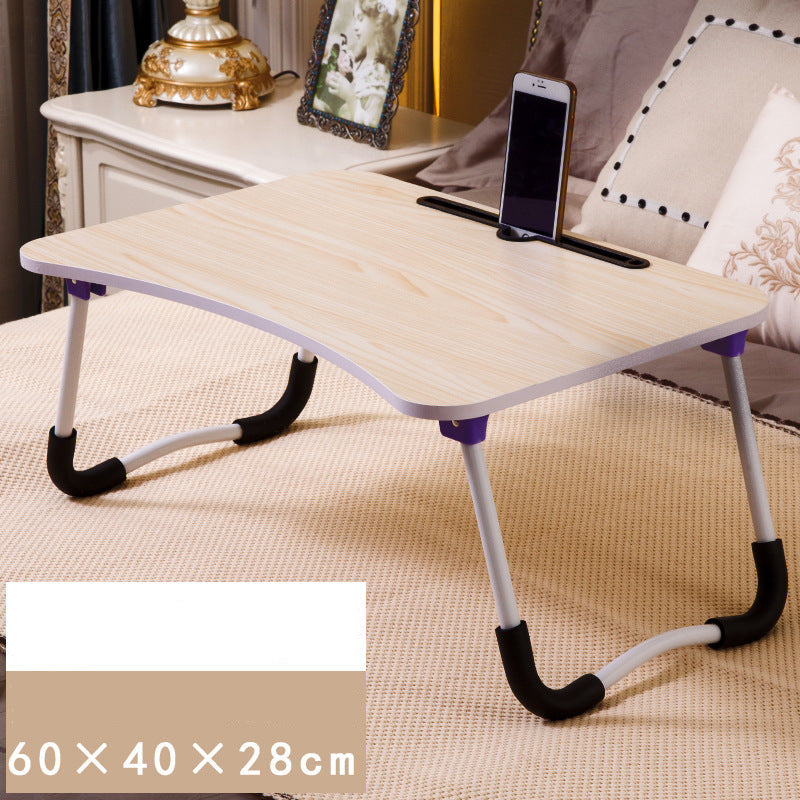 Foldable laptop desk on a bed with a phone on top, in a bedroom setting.